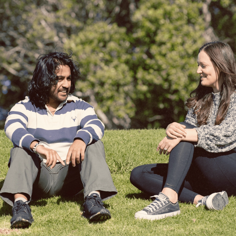 a man and a woman sit on the grass talking a man and a woman sit on the grass talking