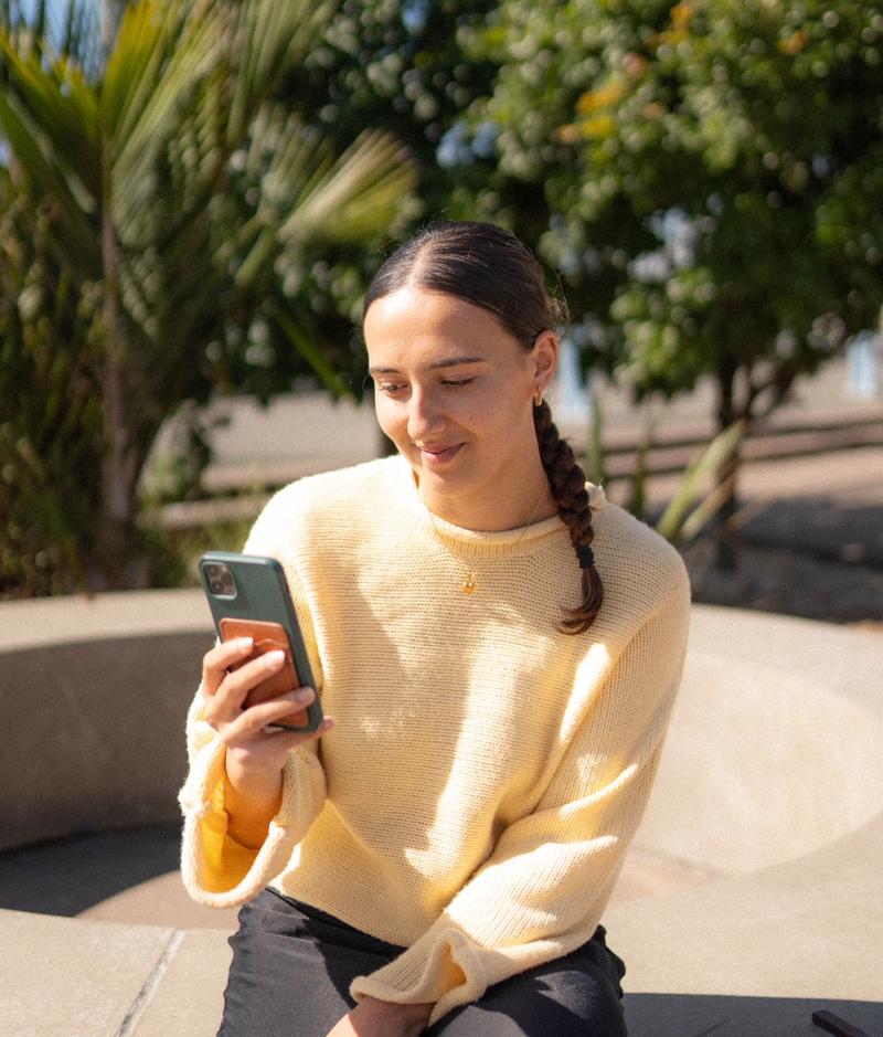 a young person sitting outside using Canteen Connect on their phone a young person sitting outside using Canteen Connect on their phone