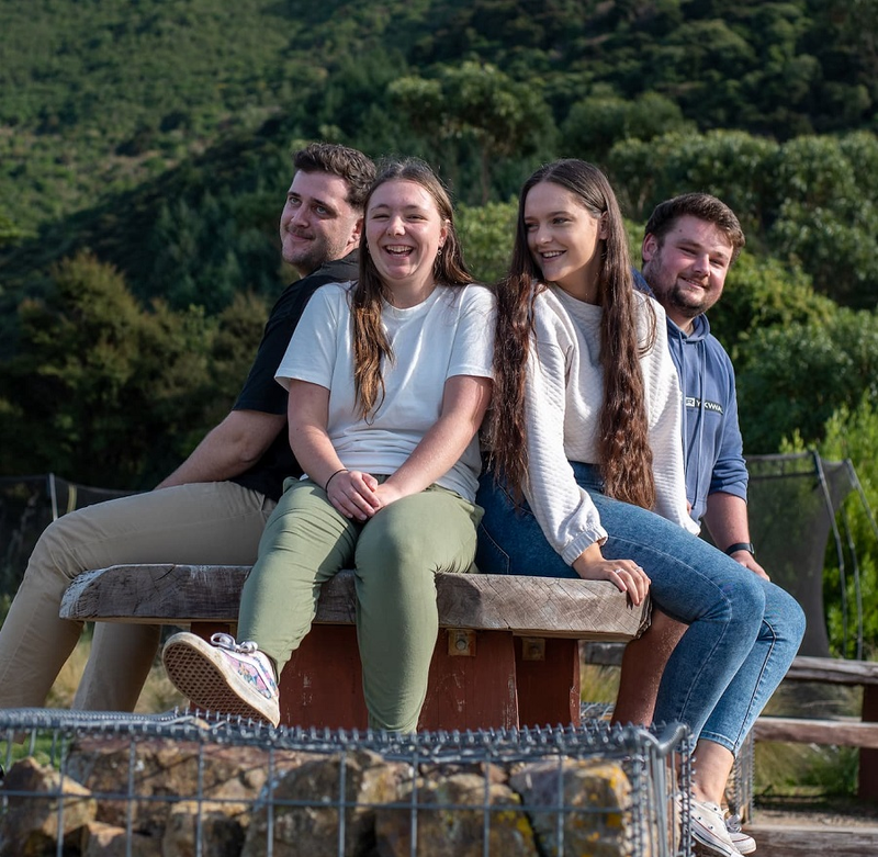 a group of people sitting on a wooden bench laughing