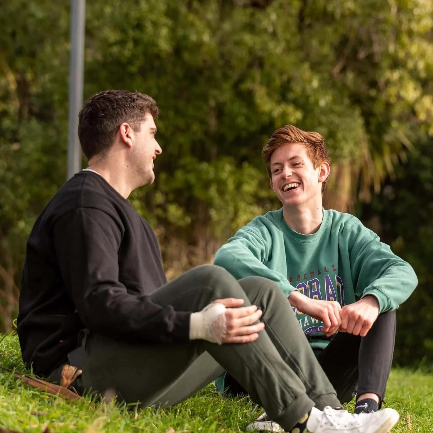 Two young people sitting down talking and laughing