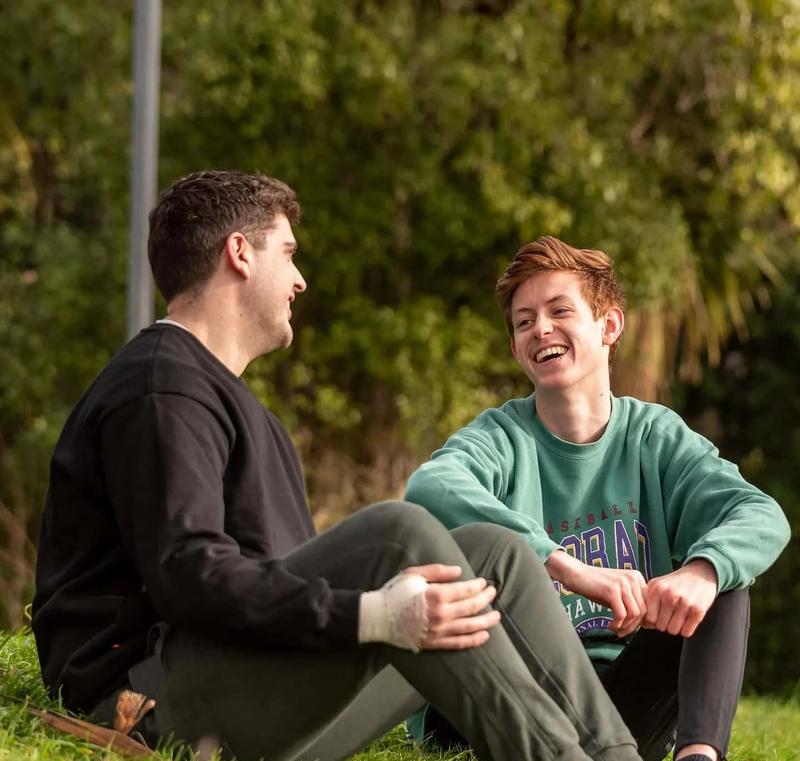 Two young people sitting down talking and laughing Two young people sitting down talking and laughing