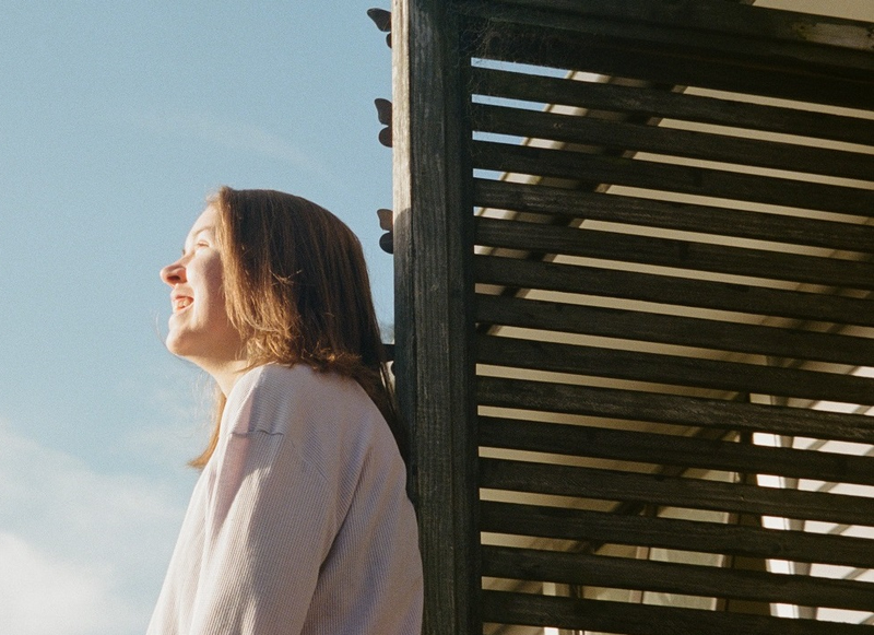 a woman leaning against a wooden fence with her eyes closed a woman leaning against a wooden fence with her eyes closed