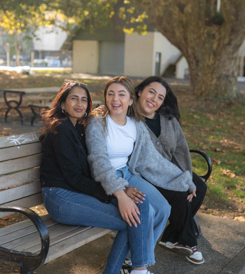 three young people sitting at a picnic table and talking three young people sitting at a picnic table and talking