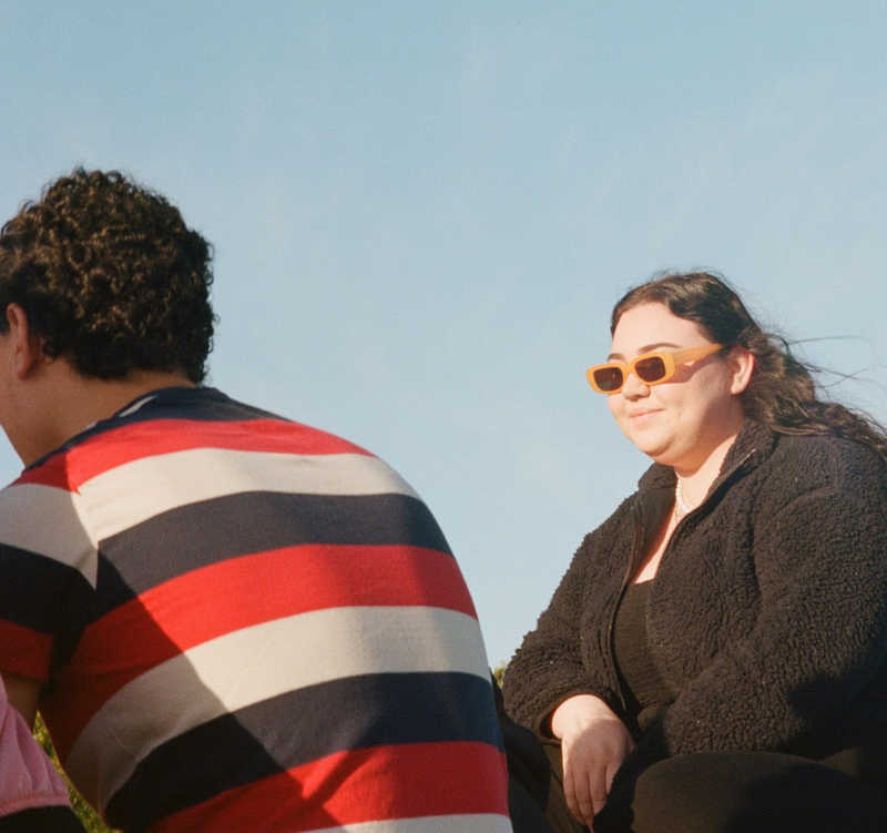 a woman wearing sunglasses sits next to a man in a striped shirt