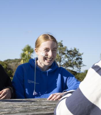 a woman wearing an oxygen mask is sitting at a picnic table . a woman wearing an oxygen mask is sitting at a picnic table .