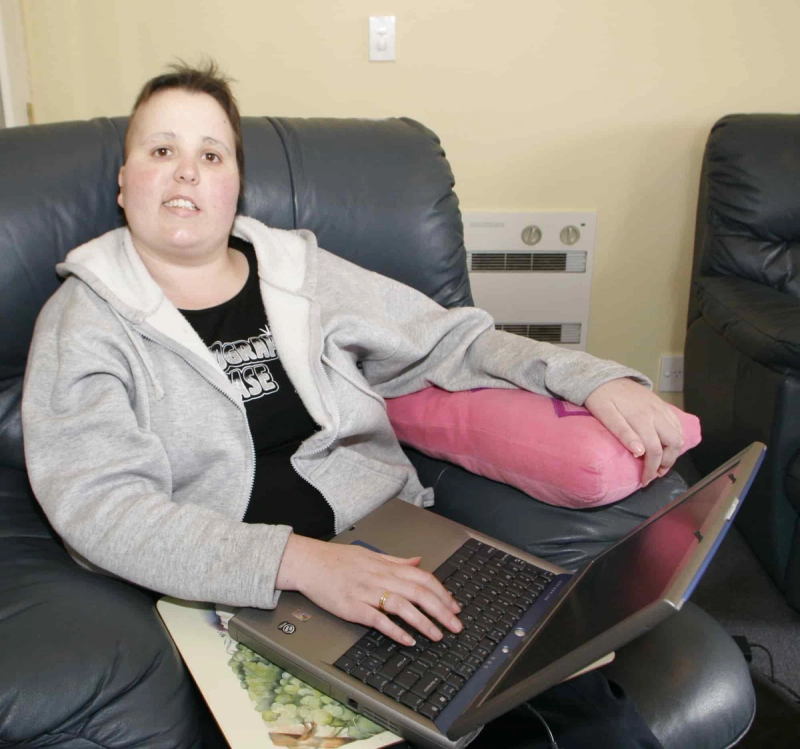a woman sitting on a couch with a laptop and a shirt that says ' acorn house ' on it a woman sitting on a couch with a laptop and a shirt that says ' acorn house ' on it