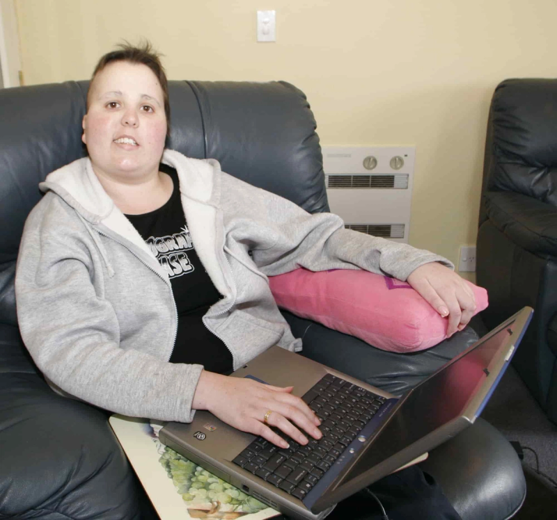 a woman sitting on a couch with a laptop and a shirt that says ' acorn house ' on it