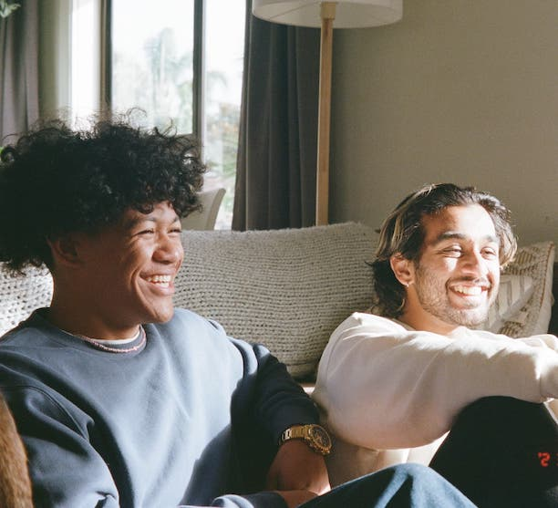 two men are sitting on a couch and one has the number 2 on his socks