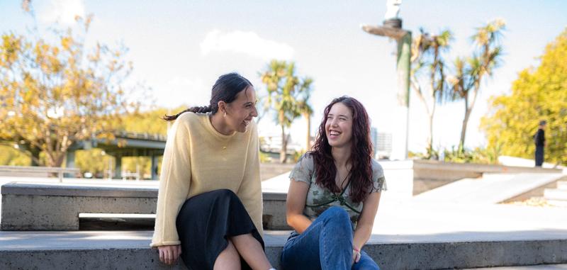 two young people impacted by cancer are walking together and laughing at a canteen programme two young people impacted by cancer are walking together and laughing at a canteen programme