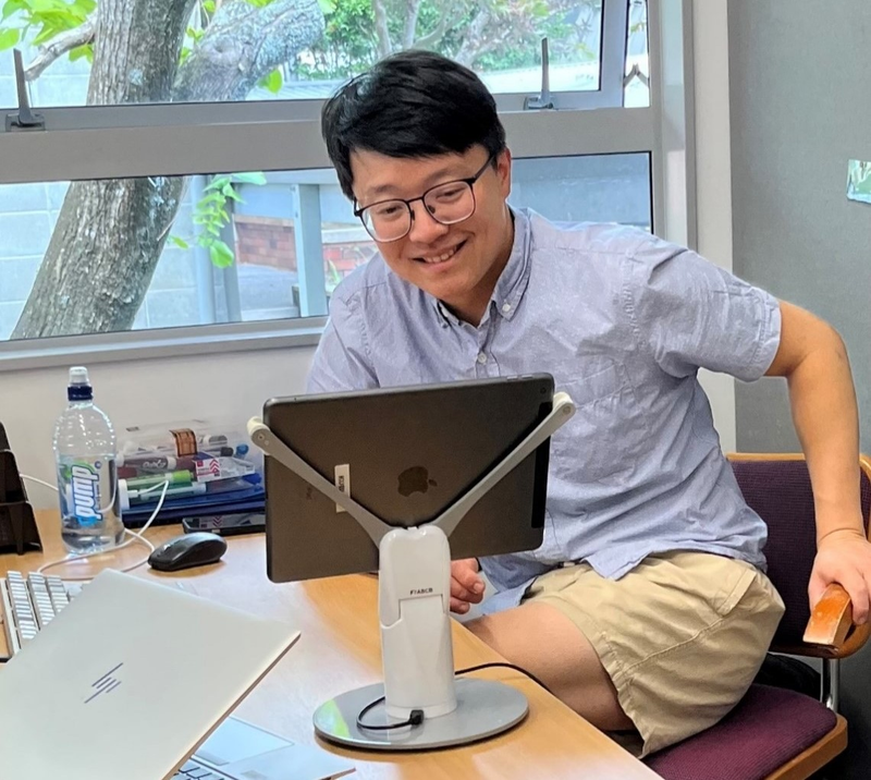 a man sits at a desk with an hp laptop and a bottle of aquafina water