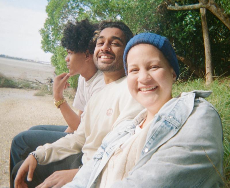 a group of people are sitting on the beach and smiling for the camera .