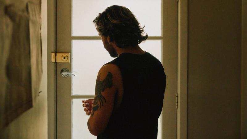 a man with a tattoo on his arm is standing in front of a door .