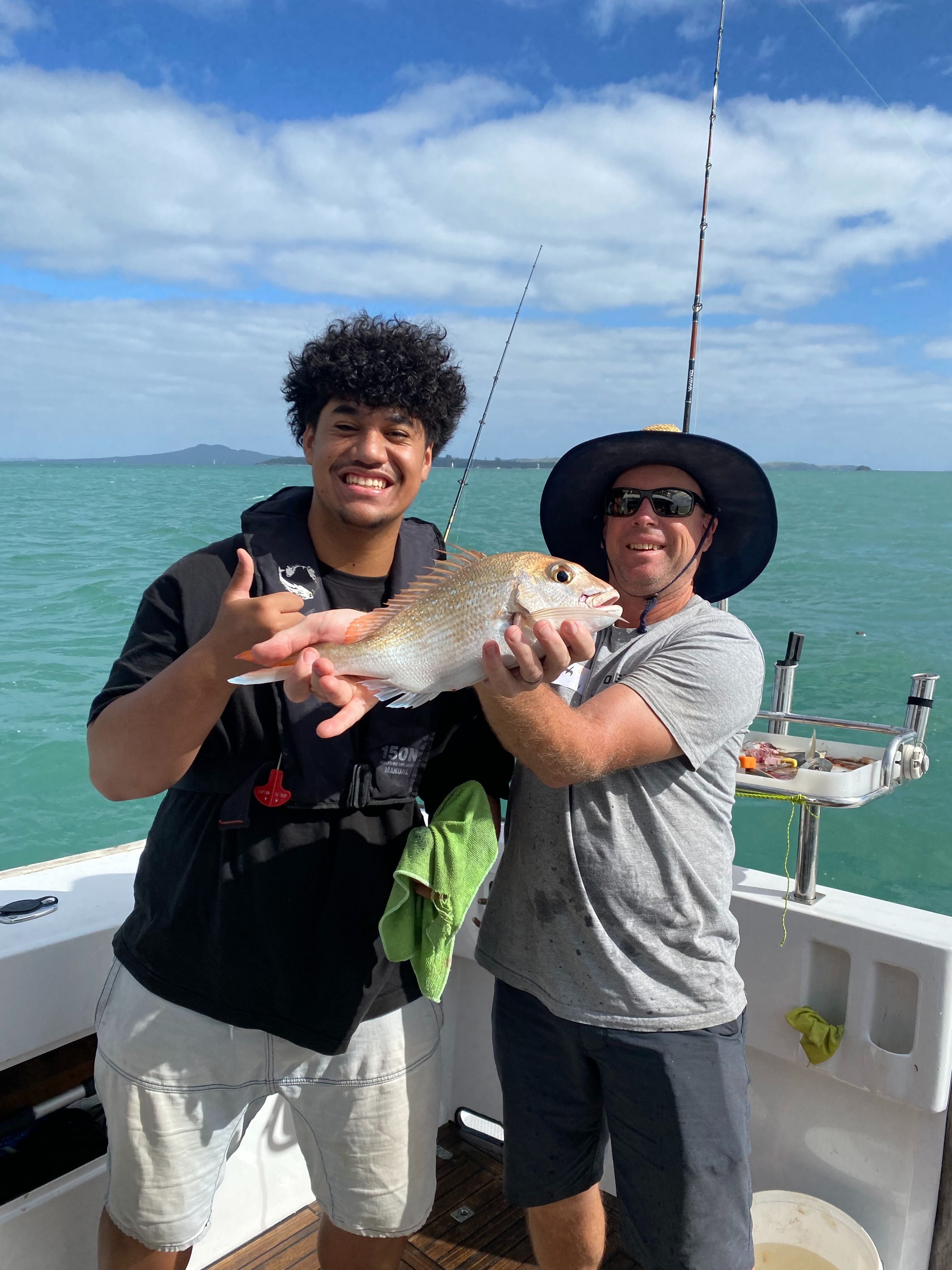 Young person and skipper smiling holding a fish