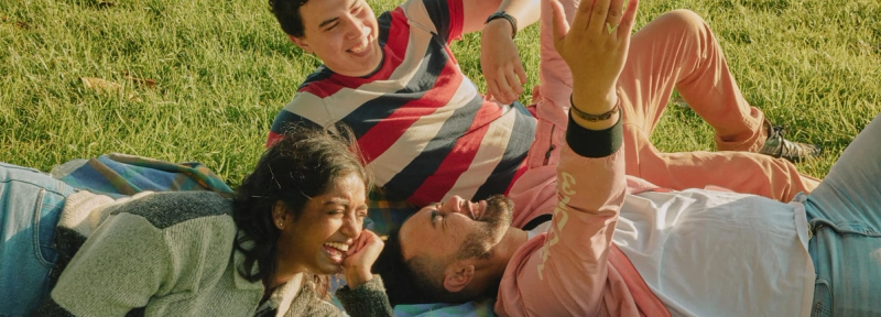 a group of people are laying on a blanket in the grass .