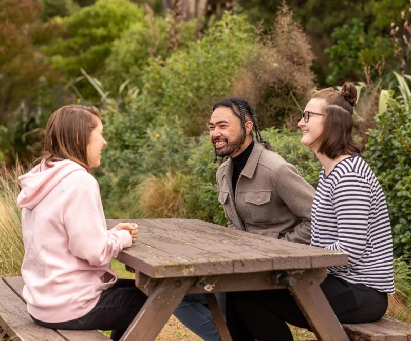 a man and two women sit at a picnic table