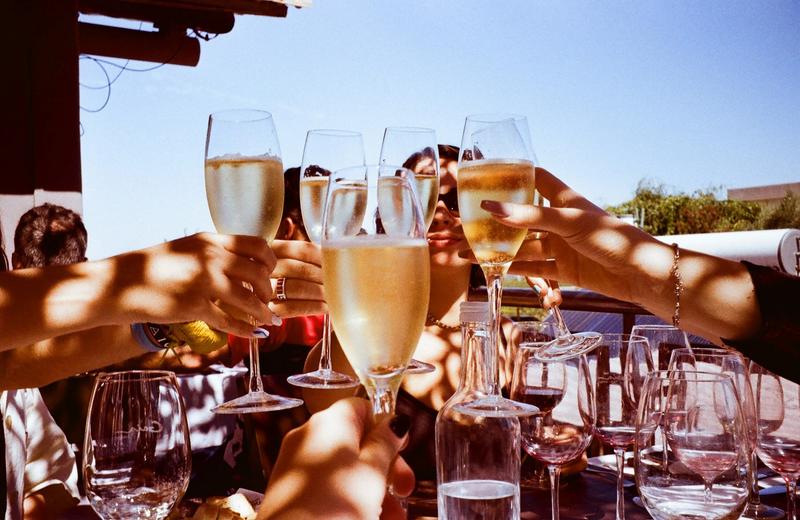 An image of people joining together glasses of sparkling white wine while celebrating.