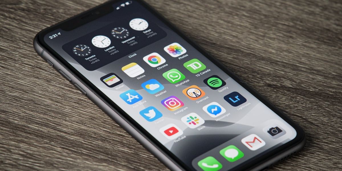 A smartphone on a wooden surface, its home screen filled with app icons.