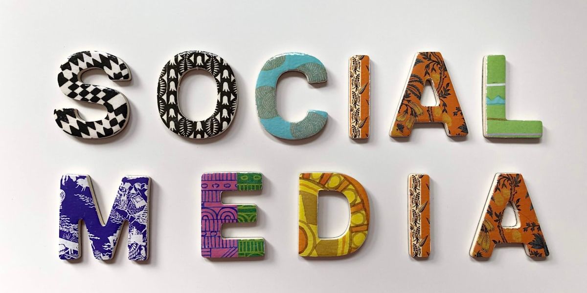 Colourful wooden letters spelling the words “social media” on a white background.