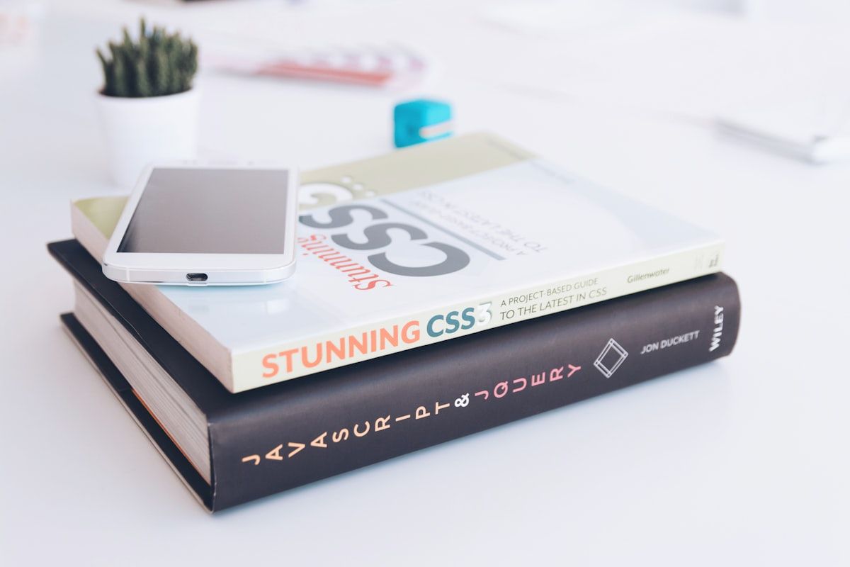 Un livre intitulé Stunning CSS posé sur une pile de livres, un téléphone dessus.