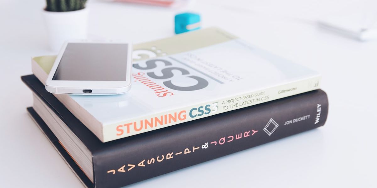 Un livre intitulé Stunning CSS posé sur une pile de livres, un téléphone dessus.
