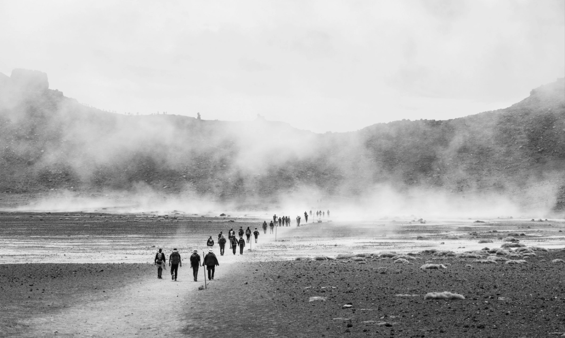 People walking on dirt path toward mountain