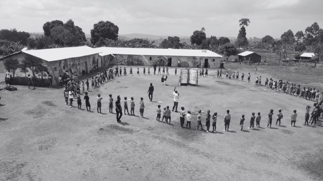 Students holding hands in a circle near a school.