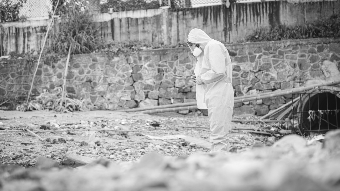 Person in hazmat suit walking over ruins.