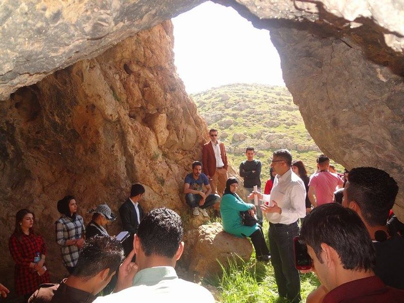 A teacher addressing students outside by a mountain