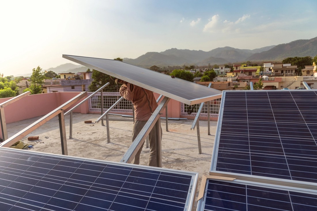 Man installs a solar panel in an Indian village.