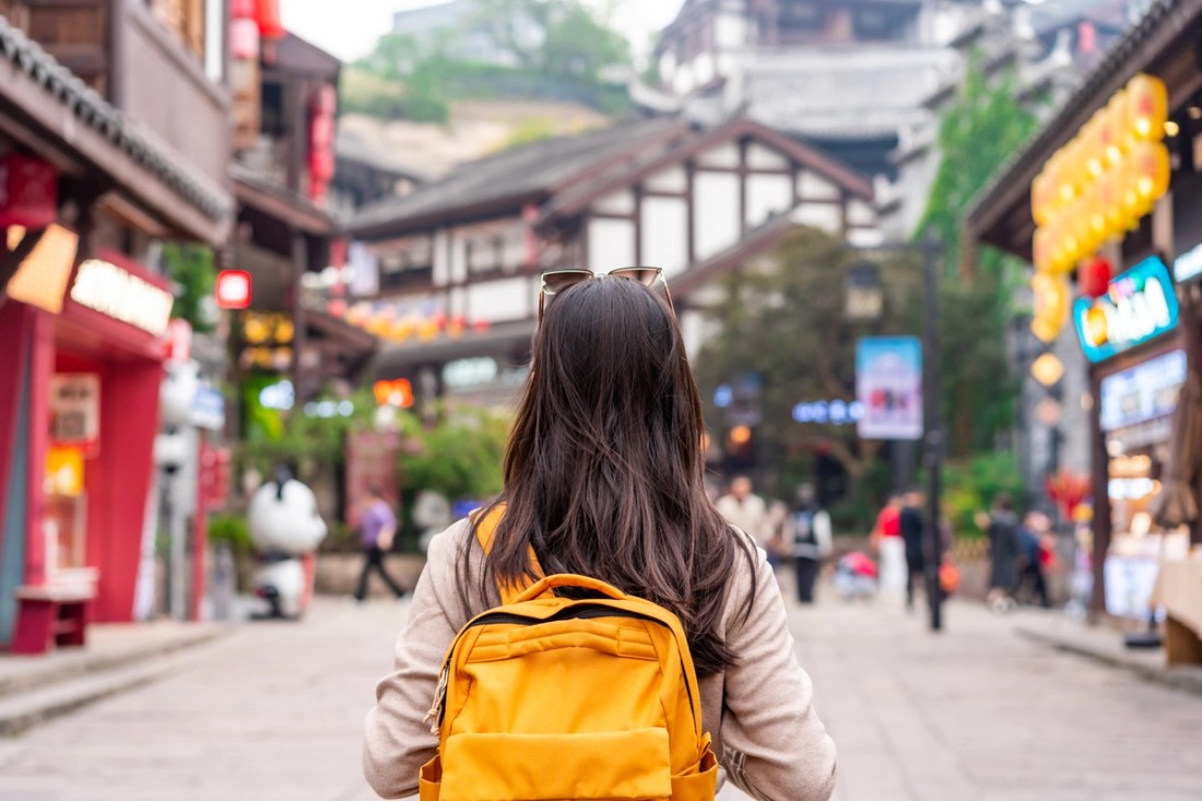 A student with a backpack walking through to a city.