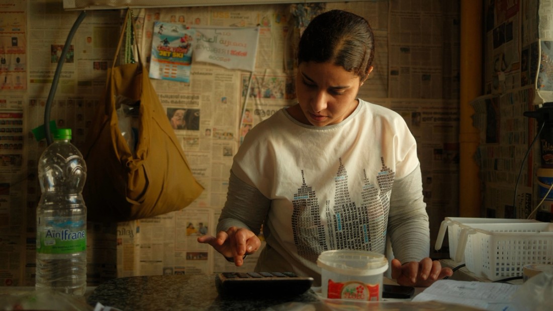 Woman works with a calculator at a crowded desk.