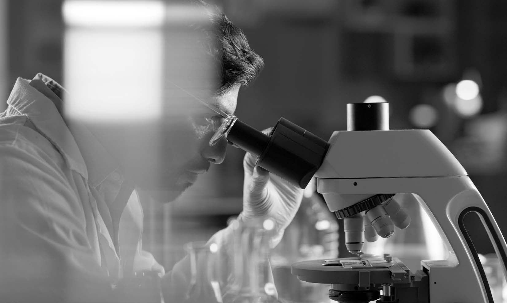 man looking through microscope.