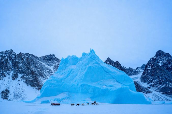 Sirius dog sledge patrol with iceberg in the background
