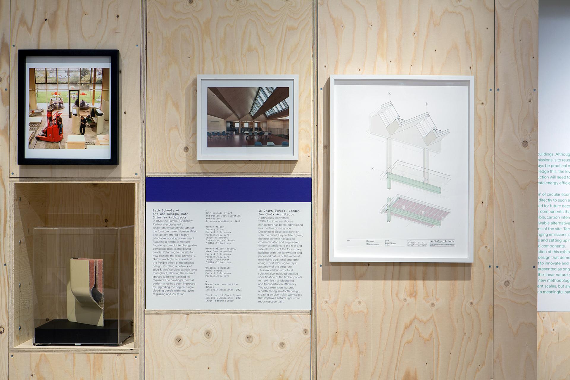 A gallery display on ply walls highlights architectural photographs, a framed technical drawing, a model in a glass case, and descriptive text exploring the role of birch ply in innovative timber construction.
