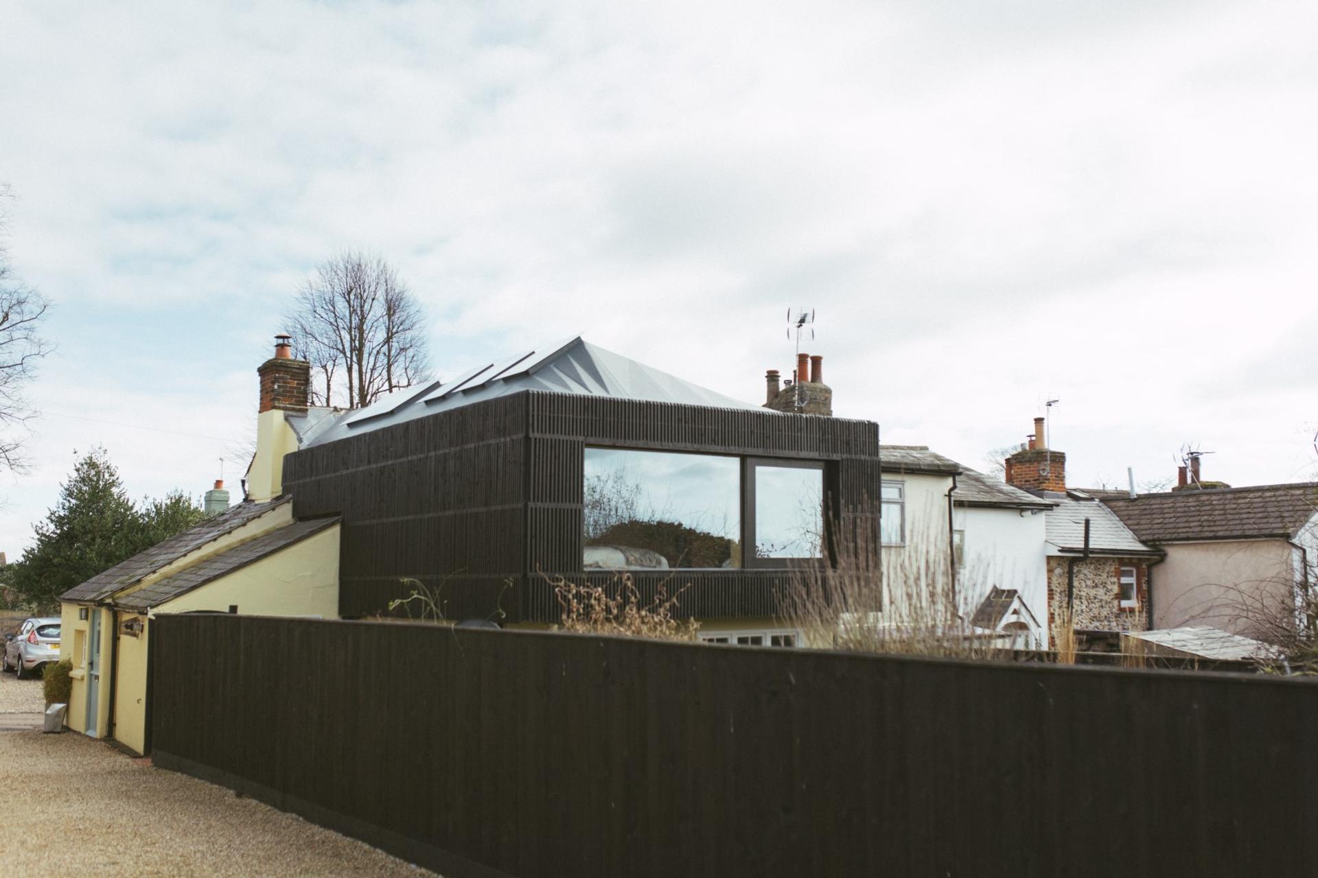 A U-Build black timber clad extension to the rear of the cottage house