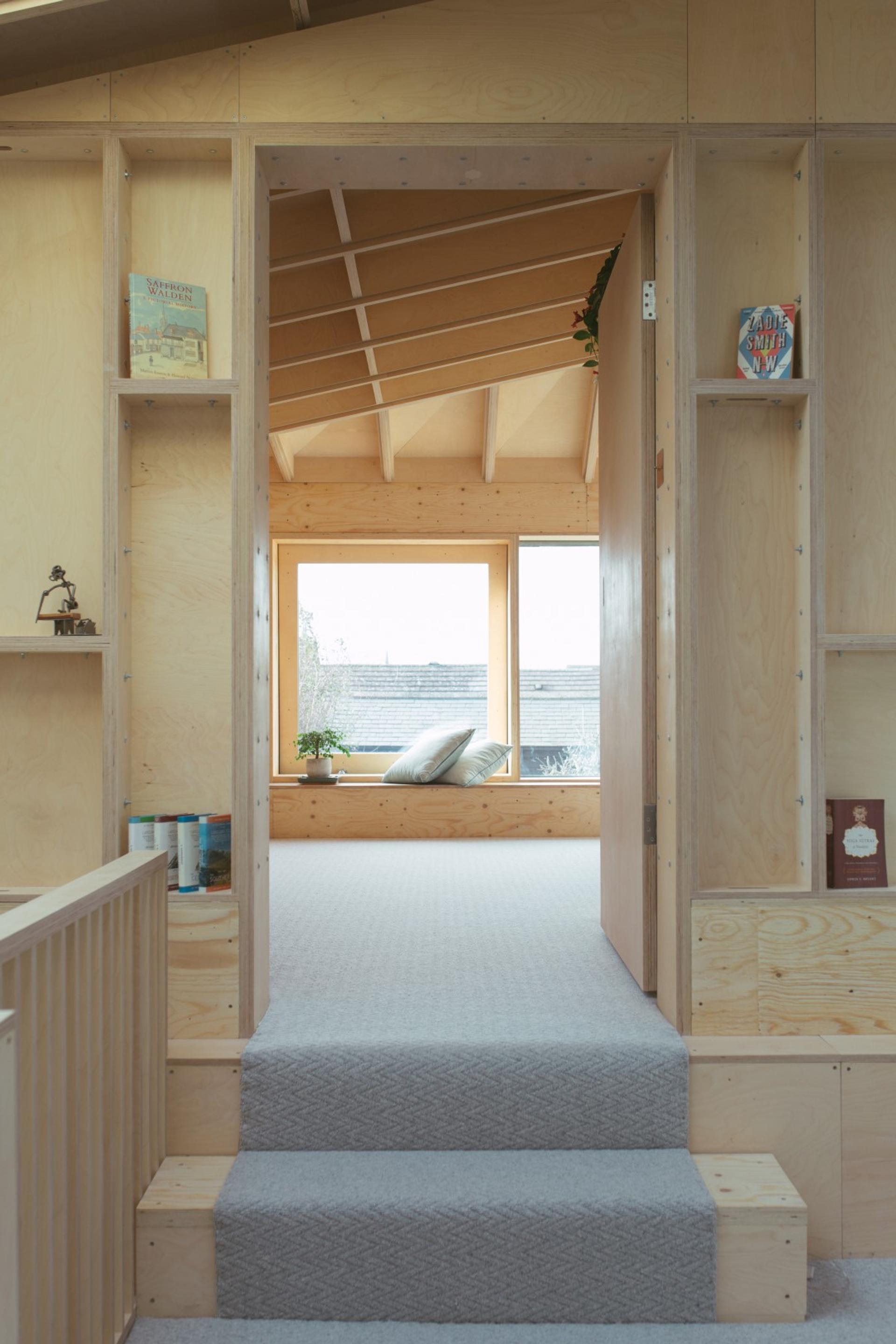 Entrance of a master bedroom with wooden walls, built in storage, large windows and skylight