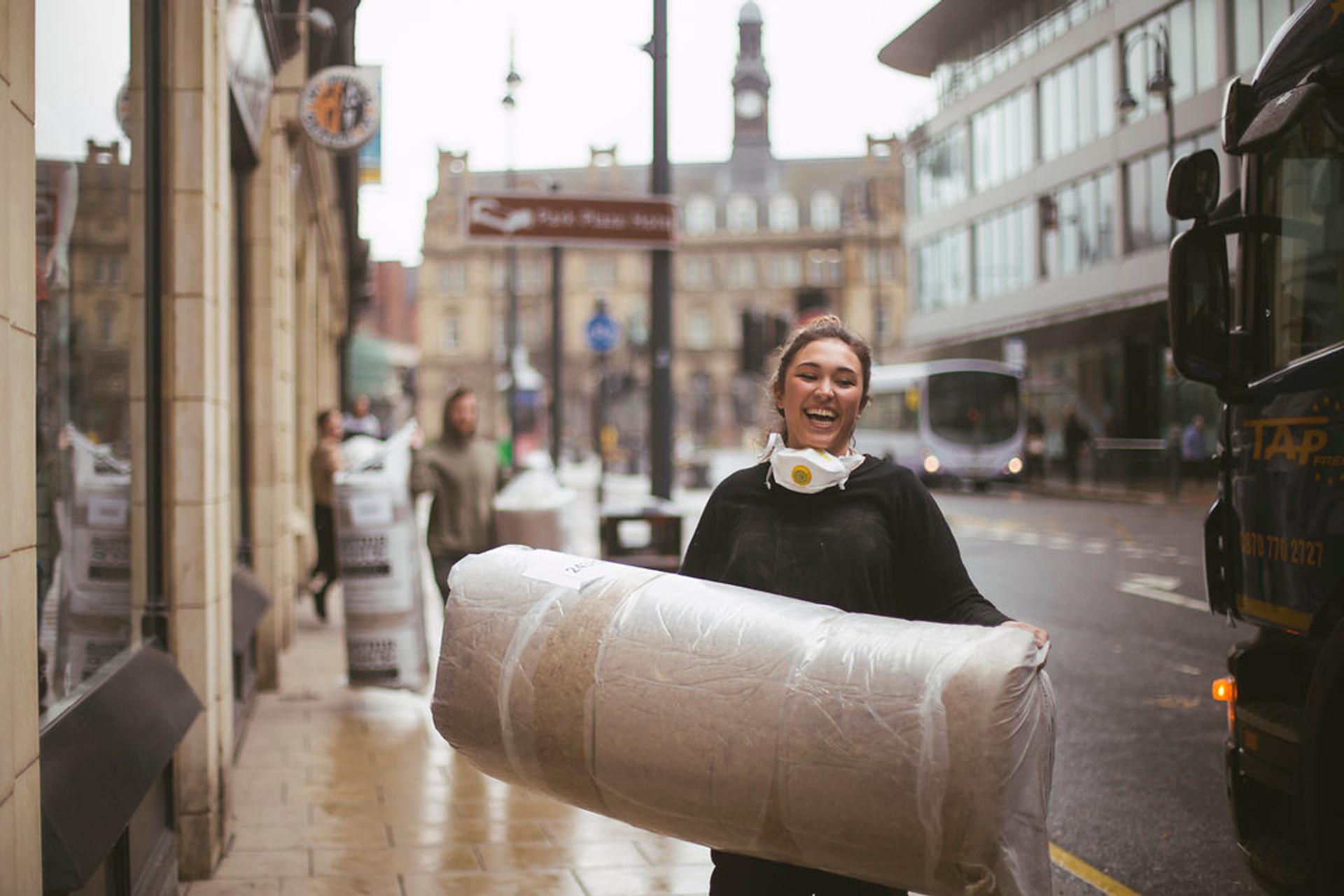 U-Build can be used for community projects - This is a picture of one of the community team carrying sheep wool insulation