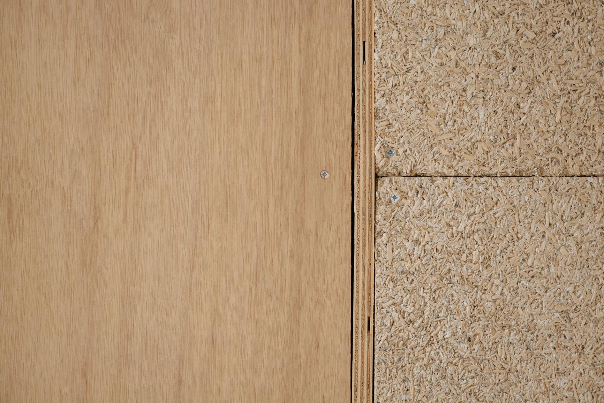 Close-up of two wood panels side by side: smooth plywood on the left and textured oriented strand board (OSB) on the right, both fastened with screws—ideal for Sustainable Ventures or sustainable business projects in Manchester.