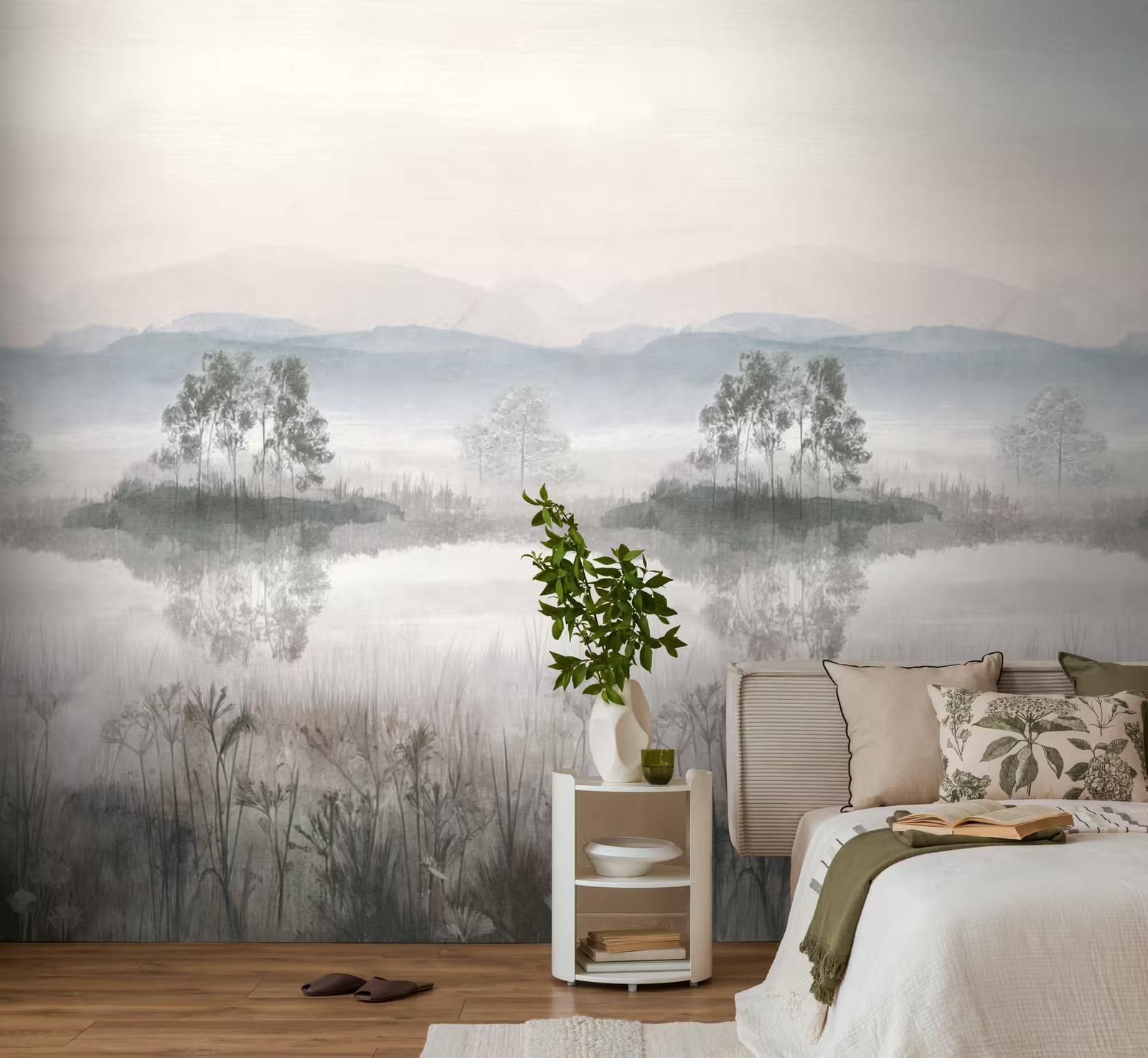 A misty lake and mountain mural in soft blue-grey behind a bed, with a small white side table and a trailing plant