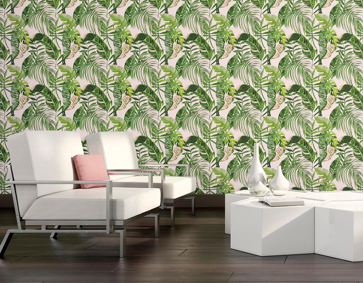 Green palm and monstera leaves on a pale pink ground, behind a white sofa and low white tables