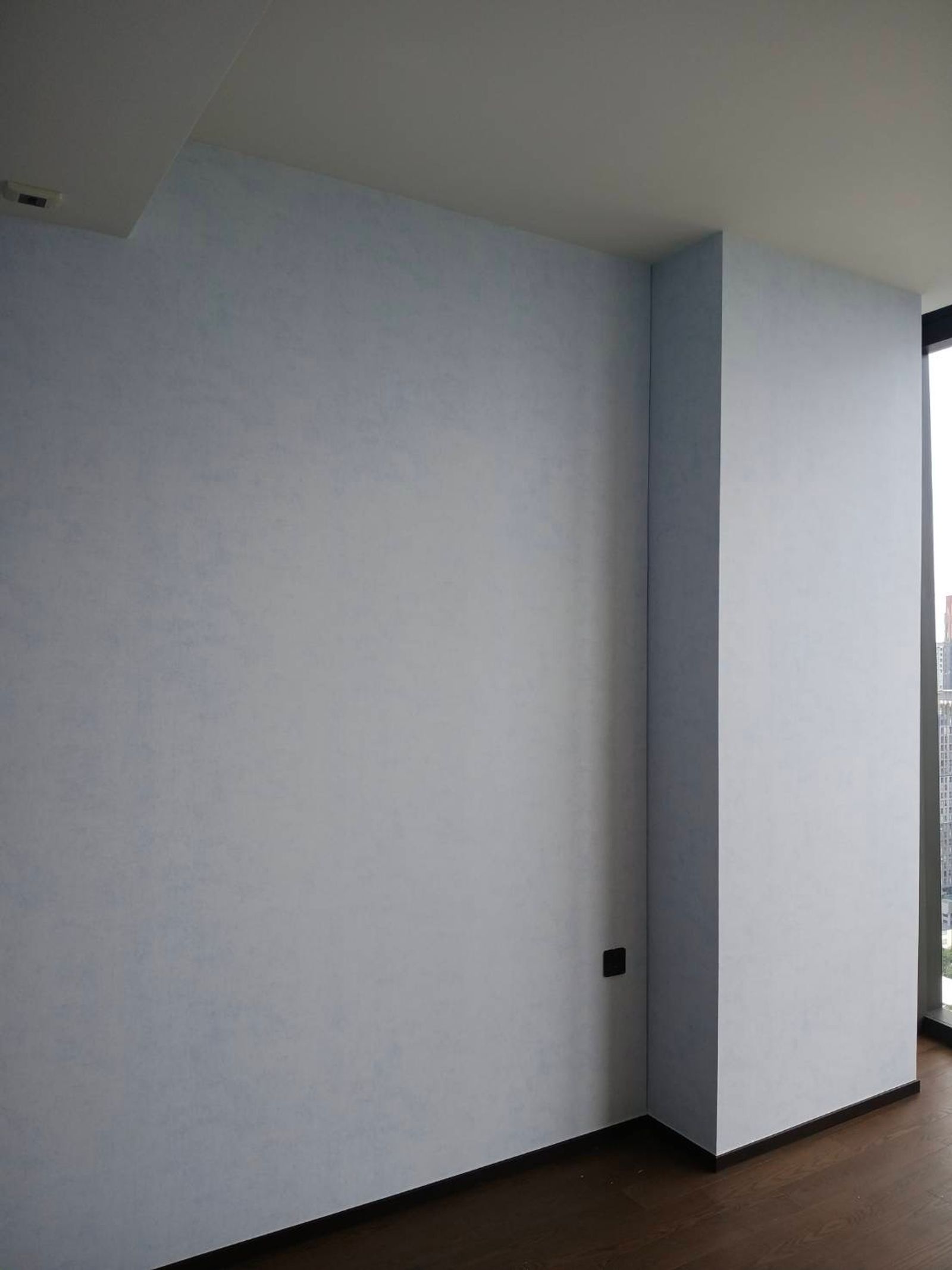 Lilly & Luis Sky Wash wallpaper in pale blue turning the corner onto the window return, the pale watercolour ground even across both walls