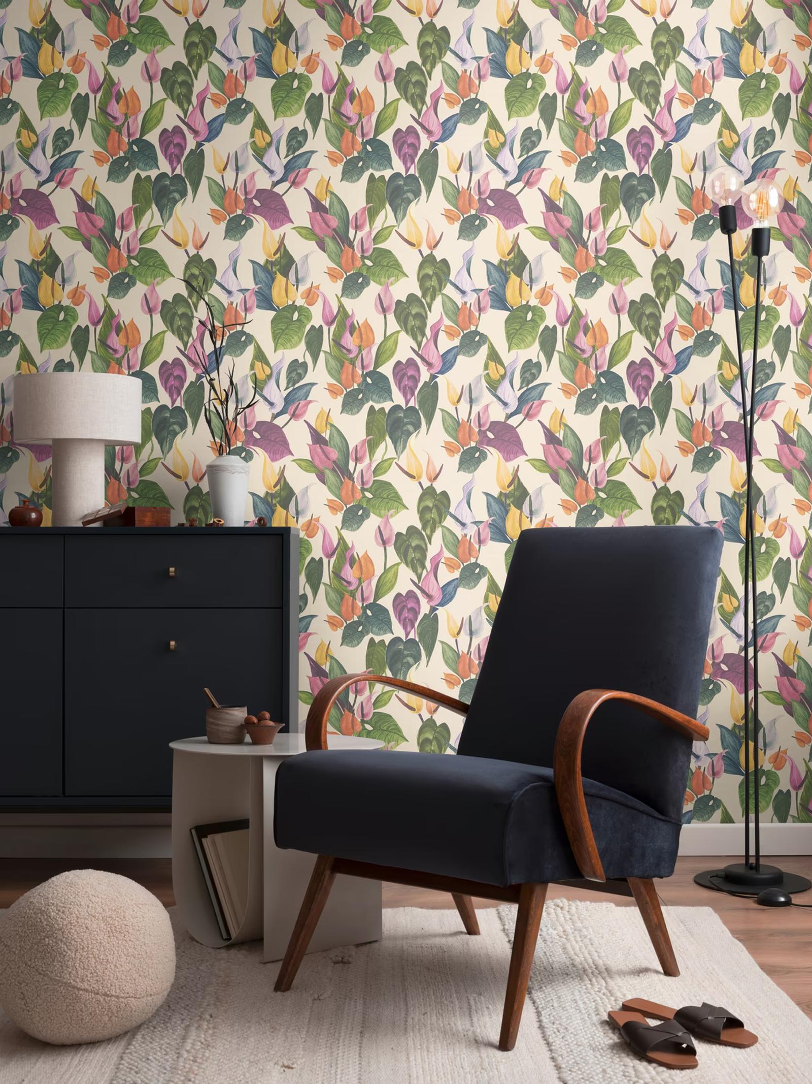 Cream Anthurium wallpaper behind a navy armchair and black cabinet