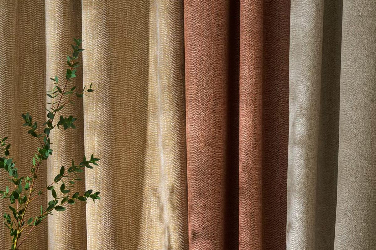 Herringbone curtains in ochre, terracotta and stone hanging in soft even folds in afternoon light