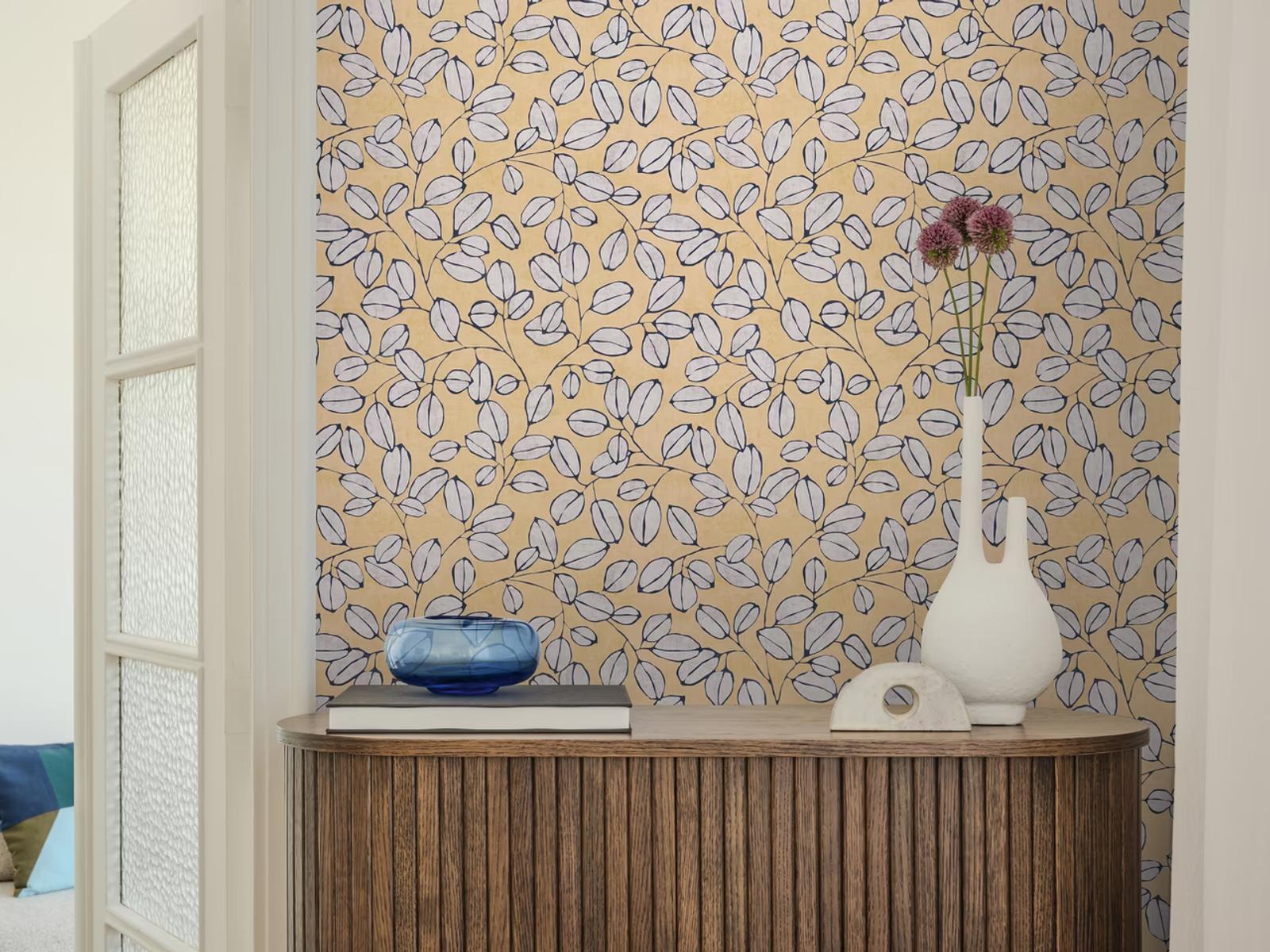Ochre Eucalyptus wallpaper in mustard above a dark fluted sideboard