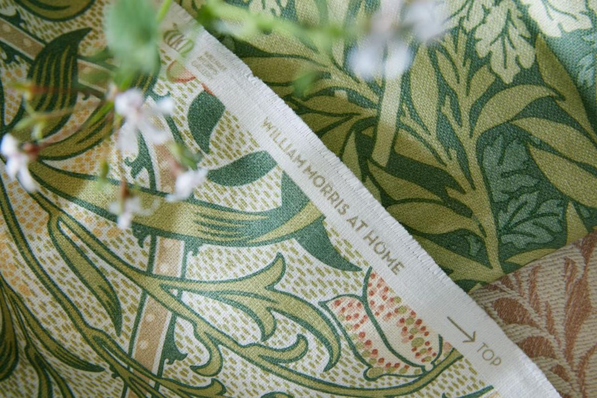 Close-up of a printed Morris fabric edge showing the woven maker's name and an arrow marked TOP
