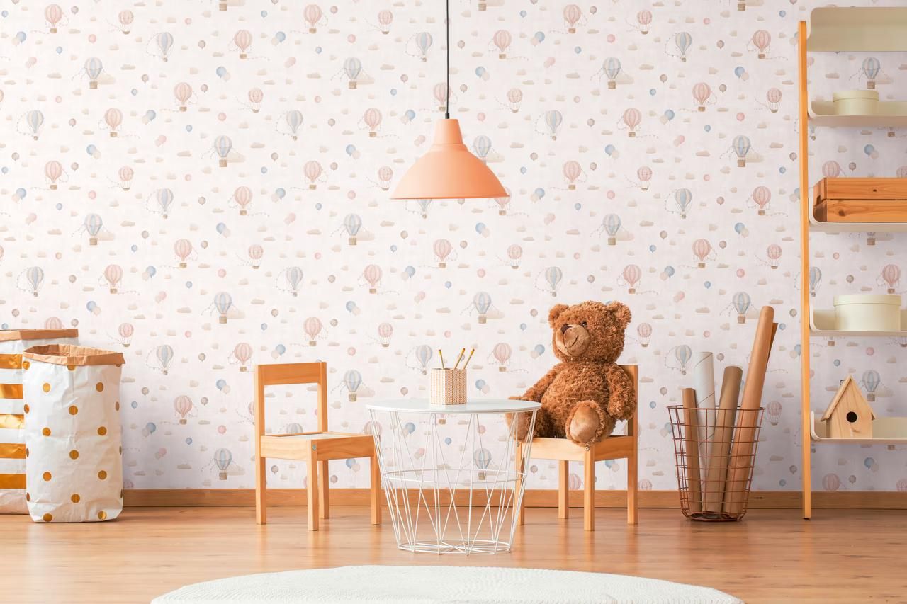 Cream Balloons wallpaper in a child's play corner, with a small wooden table, a teddy bear and a peach pendant light