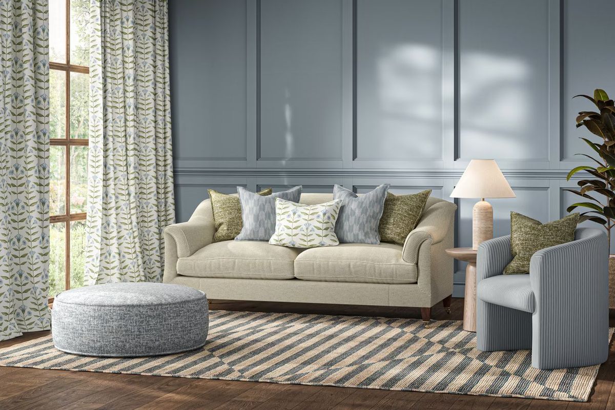 Cream sofa with patterned cushions and matching curtains against a blue panelled wall