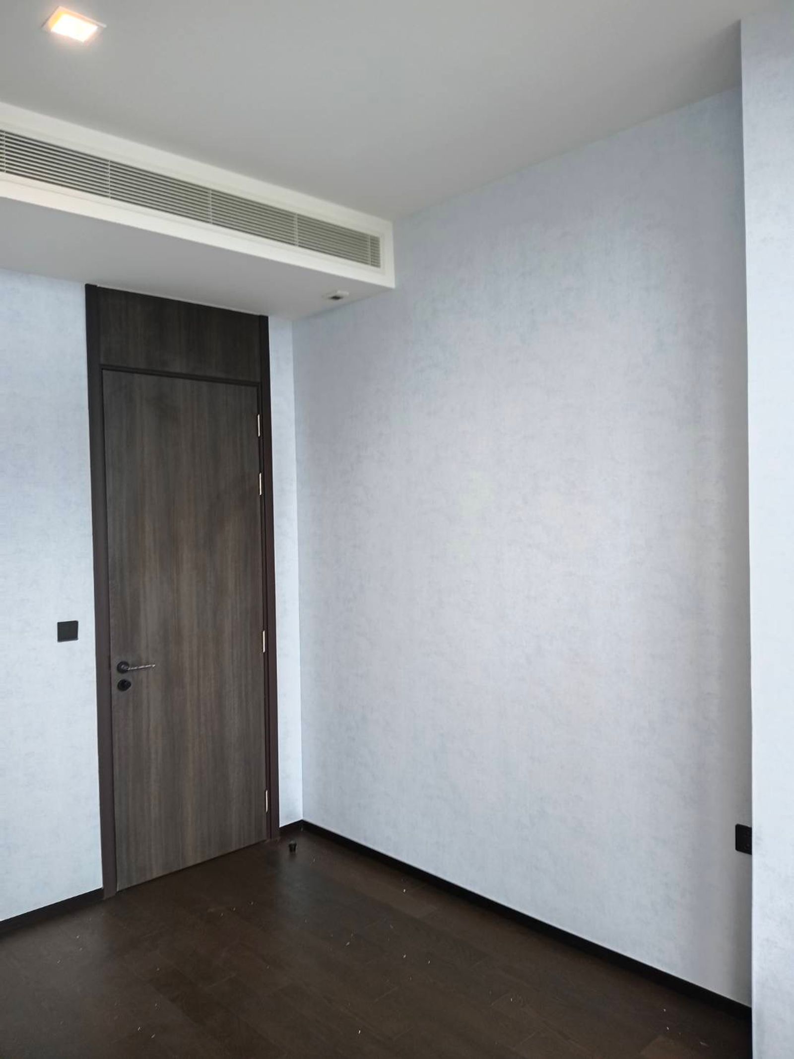 The nursery's quiet corner — Sky Wash plain wallpaper on two walls beside the timber door