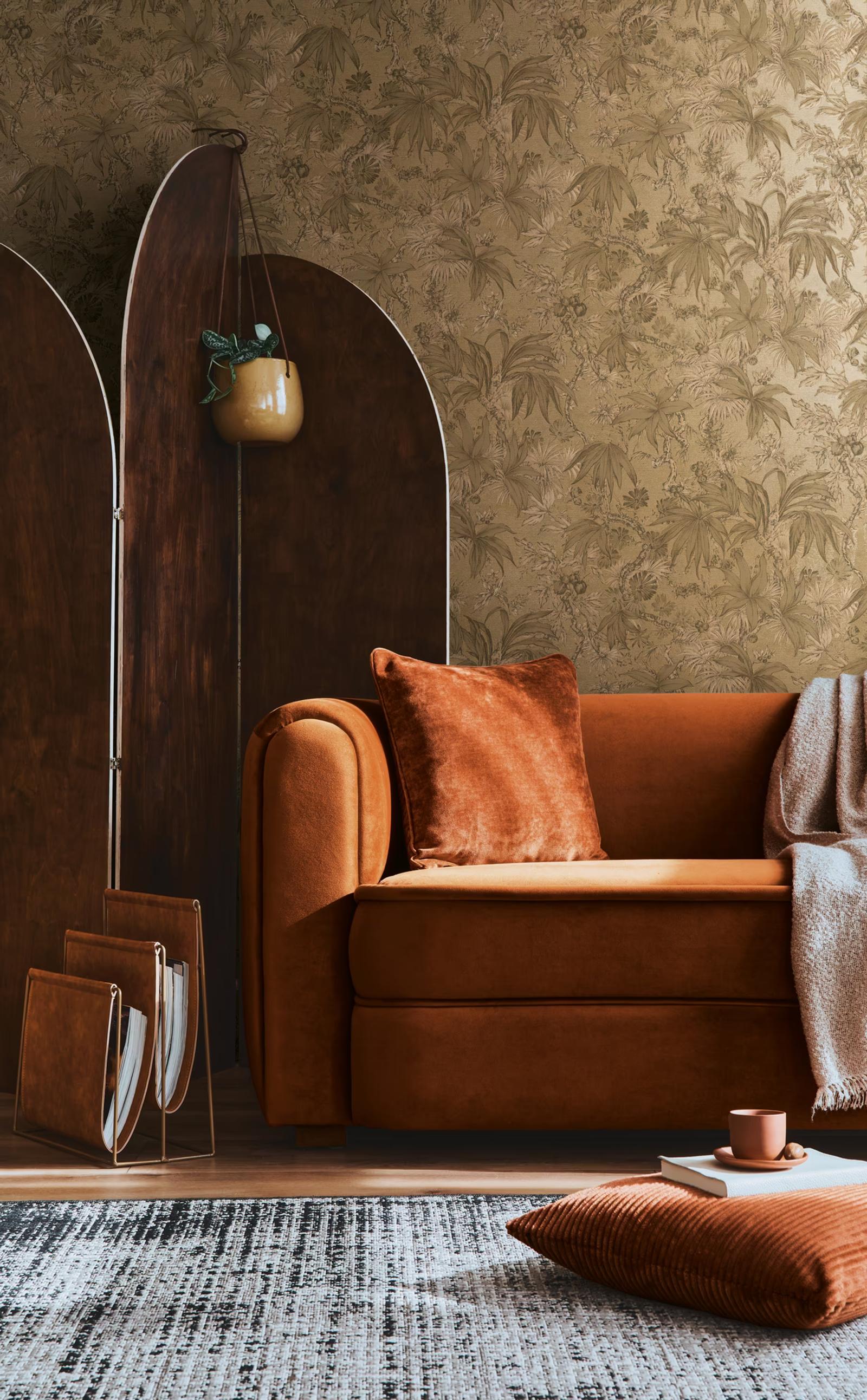 Gold Botanica wallpaper behind a burnt-orange velvet sofa
