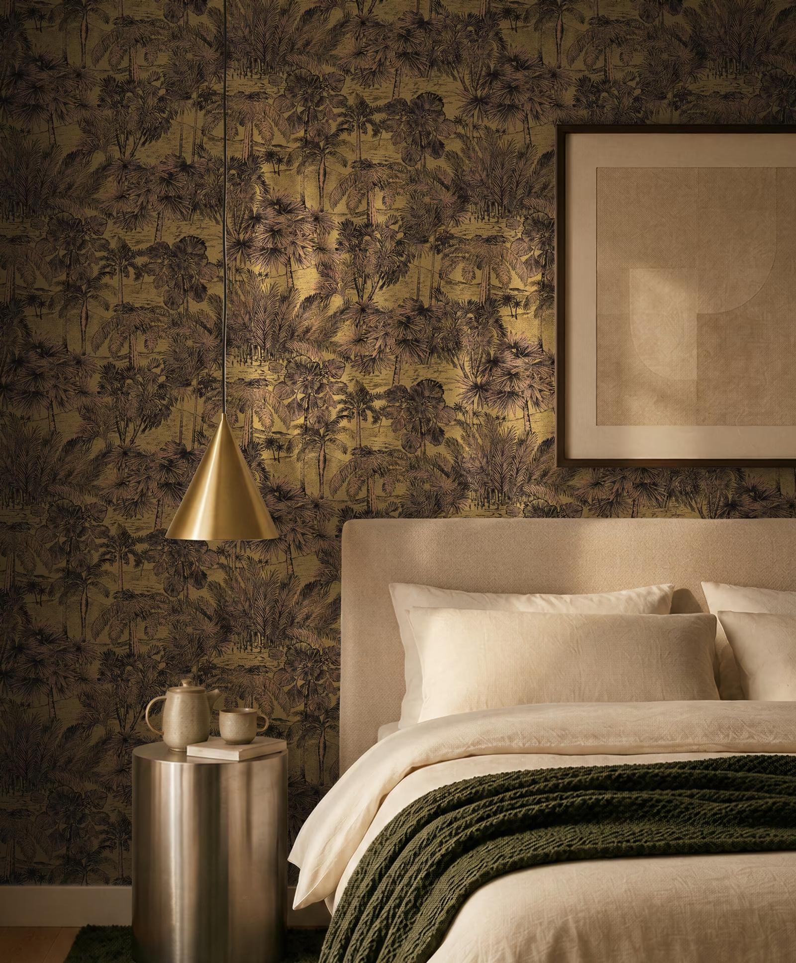 Bronze Palm Grove wallpaper behind a bed with a brass pendant lamp